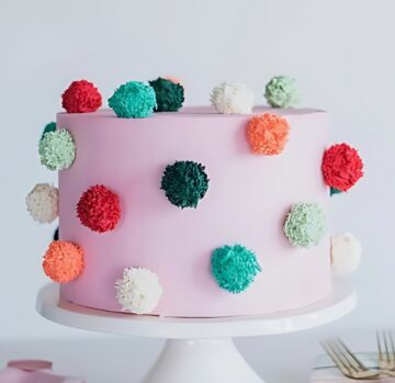Playful Pink Cake with Colorful Pom-Pom Decorations