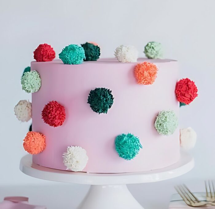 Playful Pink Cake with Colorful Pom-Pom Decorations