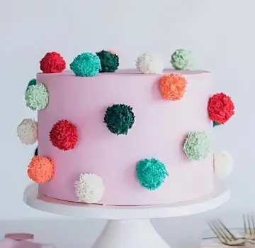 Playful Pink Cake with Colorful Pom-Pom Decorations